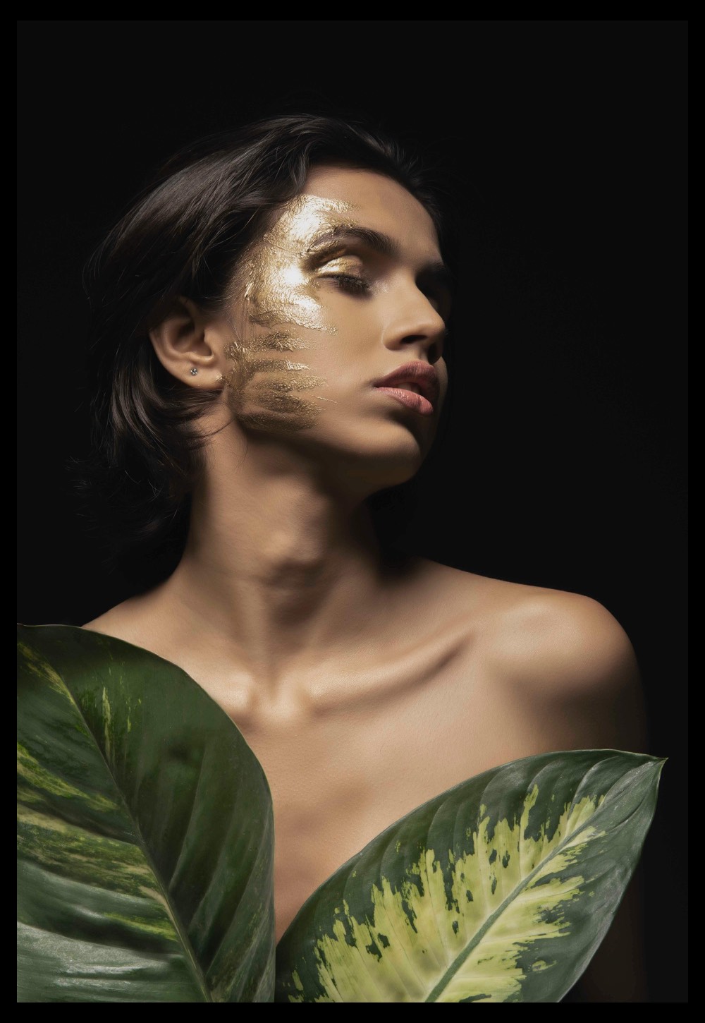 Artistic nude portrait with leaves and dark background